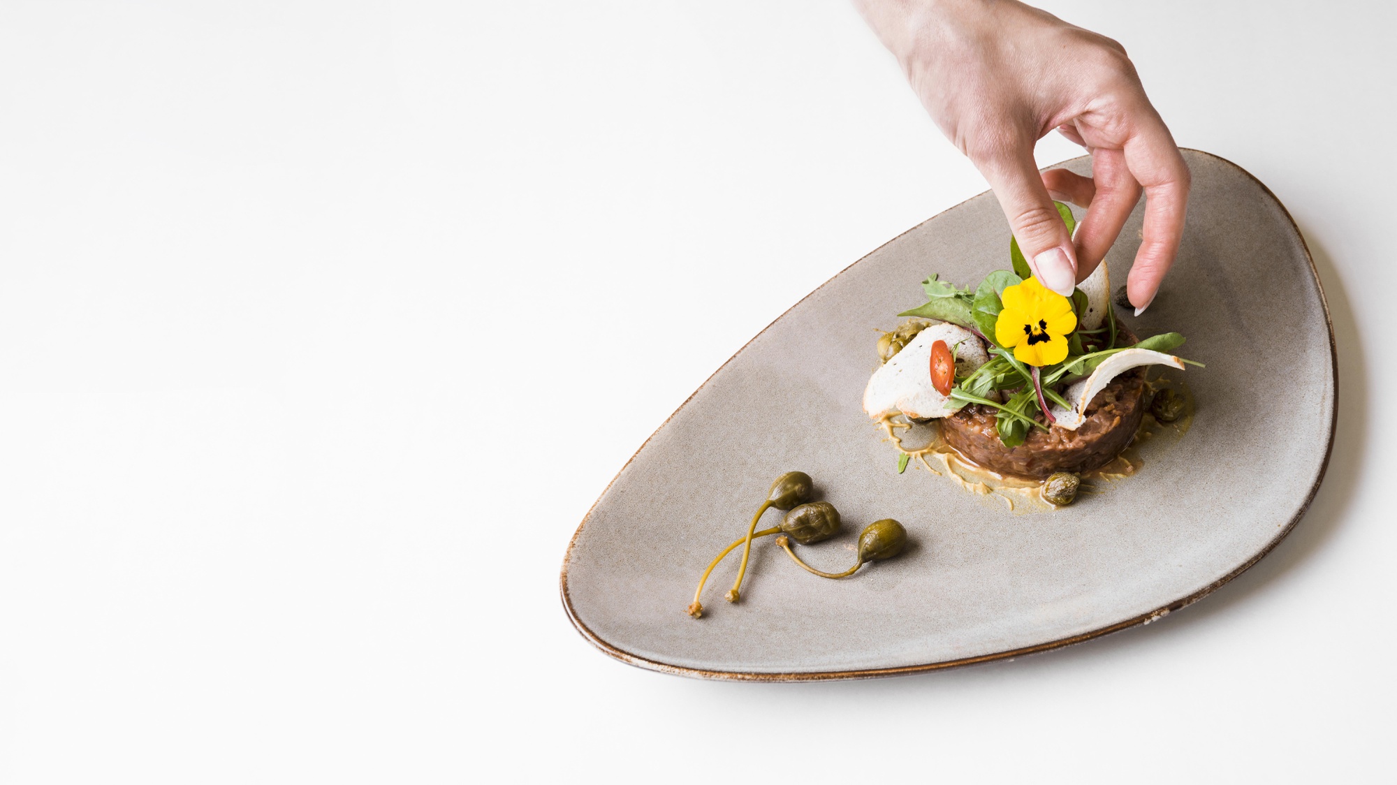 Chef preparing a plated dish on wooden table